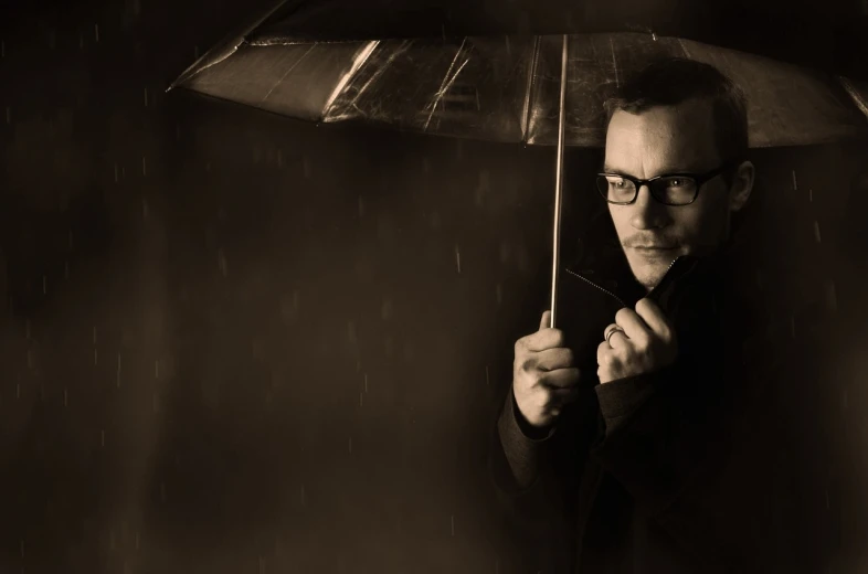 a man holding an umbrella in the rain, inspired by Yousuf Karsh, unsplash, conceptual art, man with glasses, simon pegg portrait, sepia, ben folds portrait