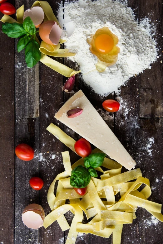 a wooden table topped with pasta and vegetables, a still life, inspired by Enzo Cucchi, pexels, made of cheese, parchment paper, also one tomato slice, dramatic product shot