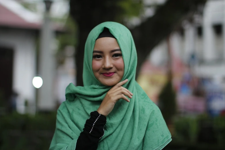 a woman in a green hijab poses for a picture, inspired by Nazmi Ziya Güran, shutterstock, hurufiyya, slight cute smile, in town, asian girl, green and black