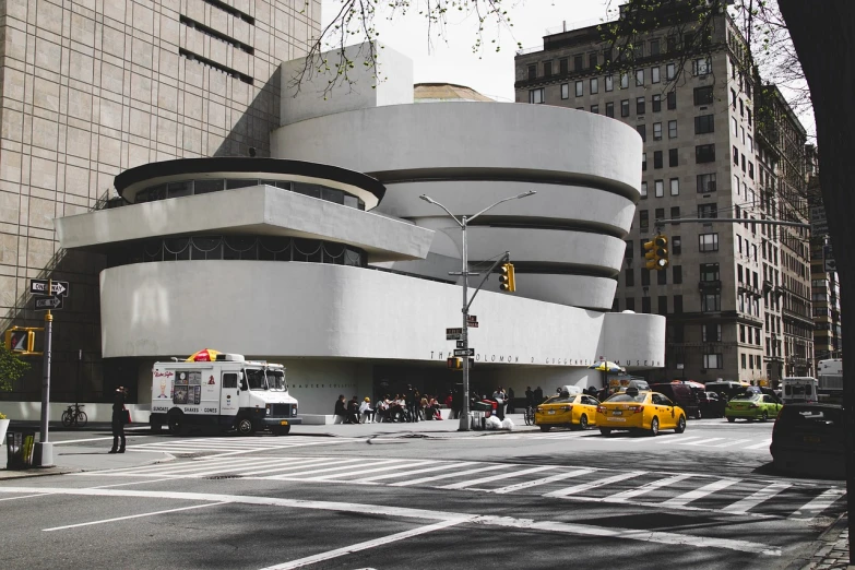 a group of cars driving down a street next to tall buildings, a photo, unsplash contest winner, modernism, frank lloyd wright, spiral, beautiful!!!! museum photo, 🦩🪐🐞👩🏻🦳