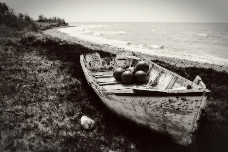 a boat sitting on top of a grass covered beach, a black and white photo, by Ihor Podolchak, pixabay contest winner, romanticism, gourds, cuban setting, fruit, aged photo