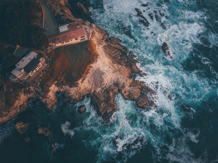 a house sitting on top of a cliff next to the ocean, by Alexander Bogen, unsplash contest winner, process art, helicopter view, bay area, soft lighting from above, violent stormy waters