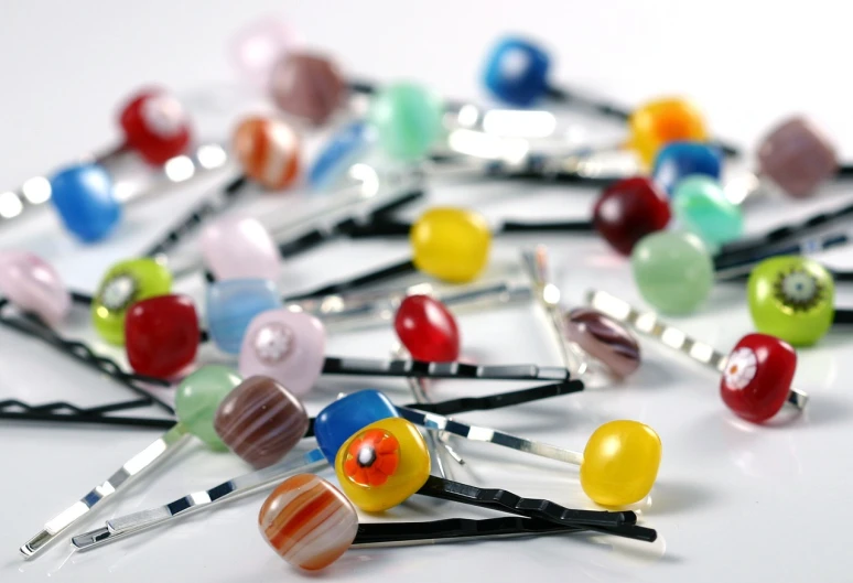 a bunch of hair pins sitting on top of a table, a pastel, bauhaus, glass beads, high quality product image”, blown glass, ghibli