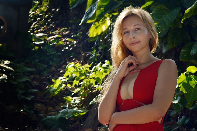 a woman in a red dress posing for a picture, a portrait, by Maksimilijan Vanka, tumblr, romanticism, in the tropical wood, blonde and attractive features, cleavage, britt marling style 3 / 4