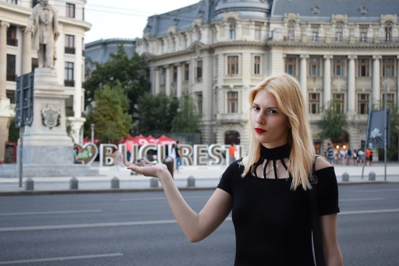 a woman in a black dress holding up a sign, a photo, inspired by Jenő Barcsay, boulevard, rubi, protest, square