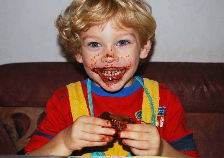 a young boy with food all over his face, a picture, chocolate frosting, meaty, full of goo, gloating