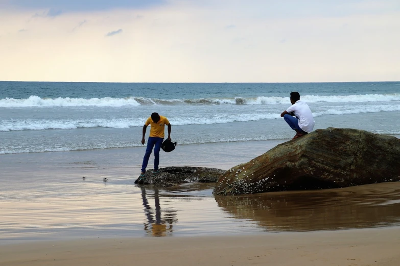 a couple of people standing on top of a rock on a beach, by Max Dauthendey, flickr, people angling at the edge, sri lankan landscape, people at work, maintenance photo