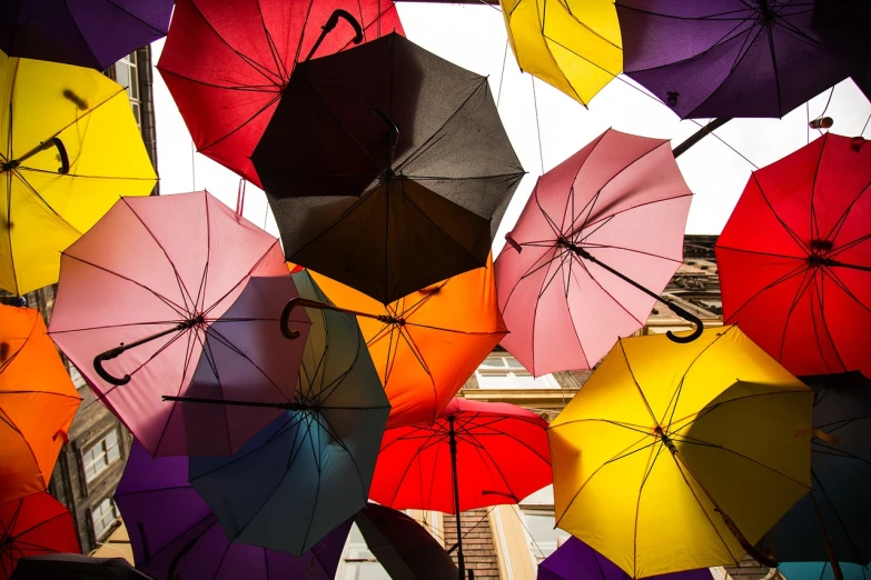 a bunch of colorful umbrellas hanging from the ceiling, a photo, by Thomas Häfner, shutterstock, street photo, different colors, stock photo, rainny