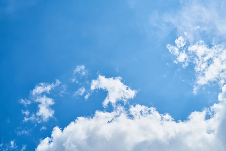 a large jetliner flying through a cloudy blue sky, a picture, by Andries Stock, shutterstock, minimalism, beautiful sky with cumulus couds, view from bottom to top, bright sunny day blue sky, stock photo