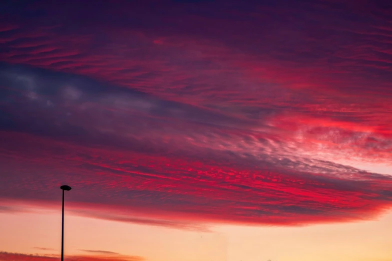 a red sky at sunset with a street light in the foreground, by Julian Allen, fine art, colorful swirly magical clouds, airplane in the sky, panorama view of the sky, great red feather