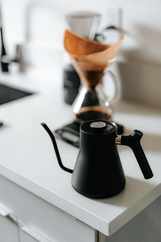 a black coffee pot sitting on top of a kitchen counter, a still life, minimalism, klein bottle, detailed cinematic shot, cone shaped, small gadget