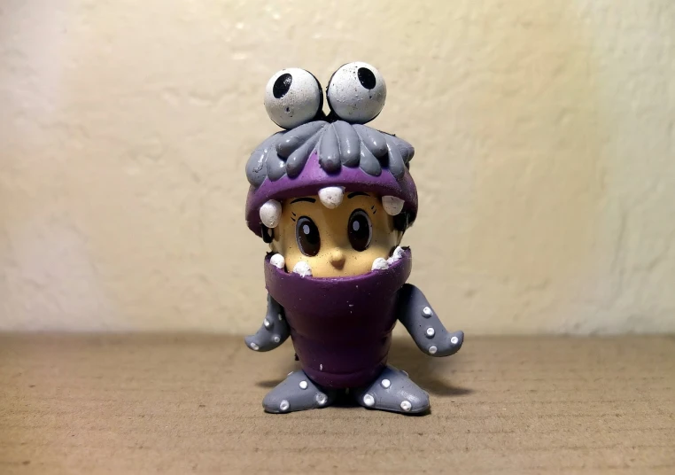 a close up of a toy on a table, a picture, inspired by Ryuzaburo Umehara, flickr, lowbrow, purple alien, mrs bean, eyes in the style of nendoroid, dressed as a scavenger
