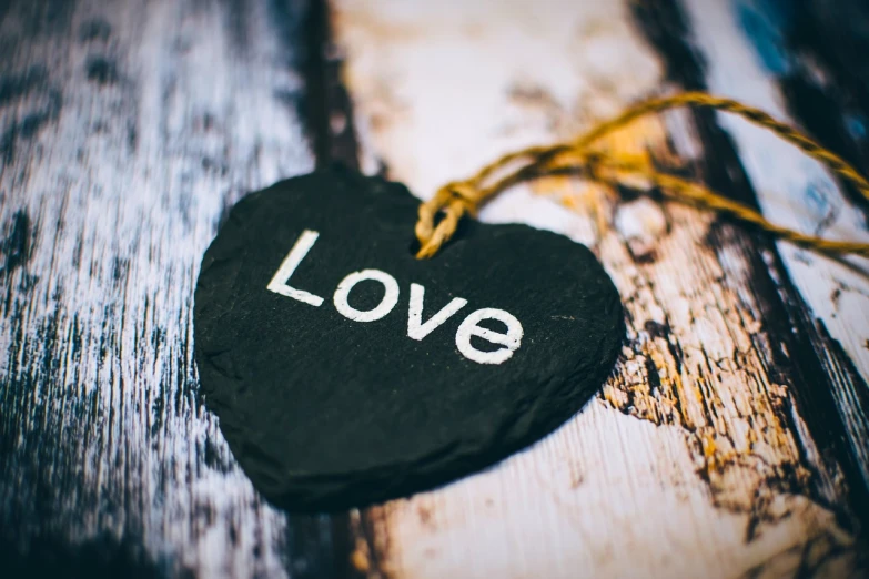 a black heart with the word love written on it, a picture, pexels, post processed, wooden, tag, rich details