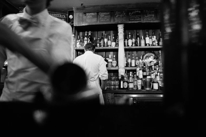 a couple of men standing in front of a bar, inspired by Larry Fink, unsplash, purism, apothecary, long shot from the back, 1 9 6 4, busy restaurant