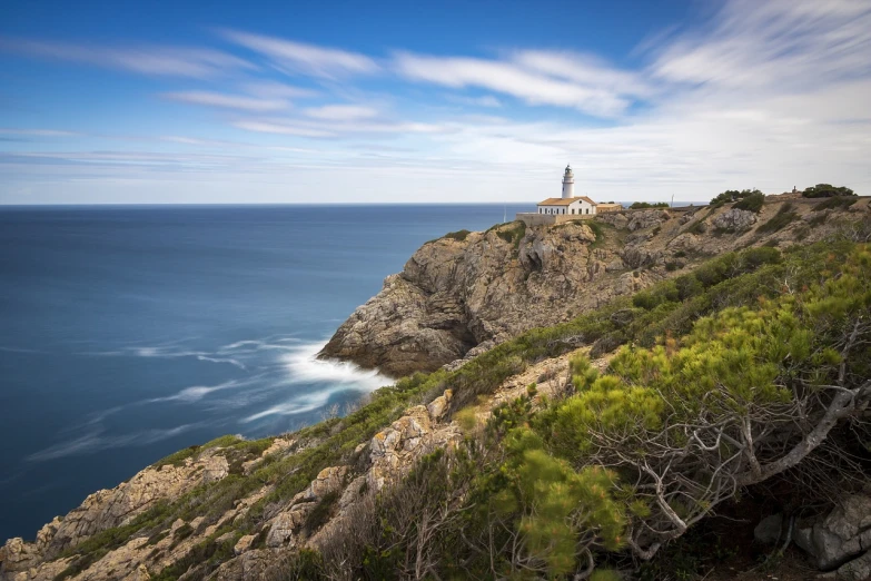 a lighthouse sitting on top of a cliff next to the ocean, a picture, by Matthias Stom, shutterstock, spain, stock photo