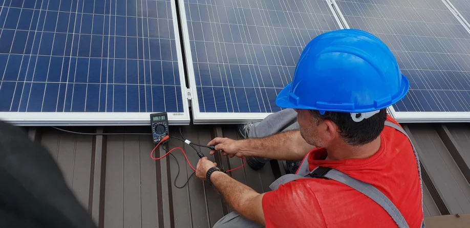 a man in a hard hat working on a solar panel, by Xul Solar, bauhaus, electrical wiring!, 🕹️ 😎 🔫 🤖 🚬, very accurate photo, album photo