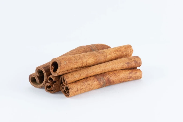 a pile of cinnamon sticks on a white surface, antipodeans, miniature product photo, detailed product photo, product introduction photo