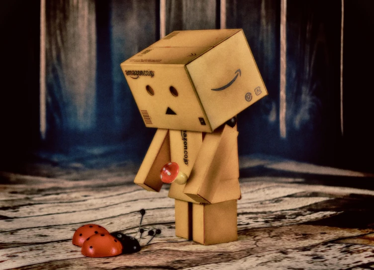 a figurine of a man with a box on his head, a picture, inspired by Sam Havadtoy, pixabay contest winner, neo-dada, ladybug robots, sad atmosphere, funko pop”, sepia photography
