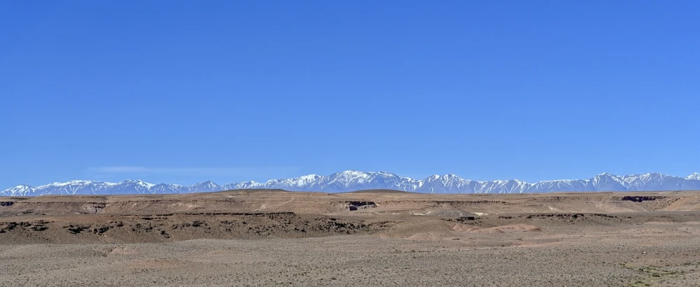 a man flying a kite in the middle of a desert, by Altichiero, flickr, les nabis, snow capped mountains, marrakech, panorama, mars landscape