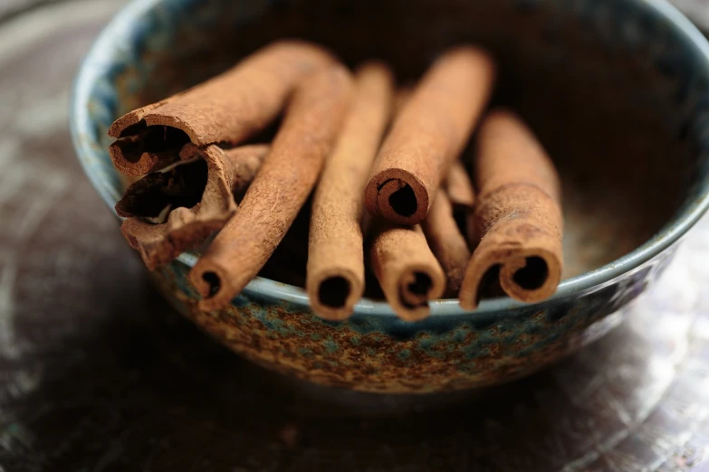 a bowl filled with cinnamon sticks on top of a table, a macro photograph, renaissance, amanda lilleston, pepper, herb, arabian
