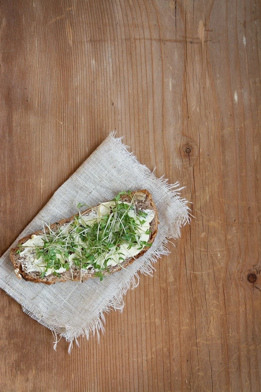 a piece of bread sitting on top of a wooden table, a portrait, by Thomas Crane, minimalism, salad and white colors in scheme, clover, food blog photo, best mayonnaise