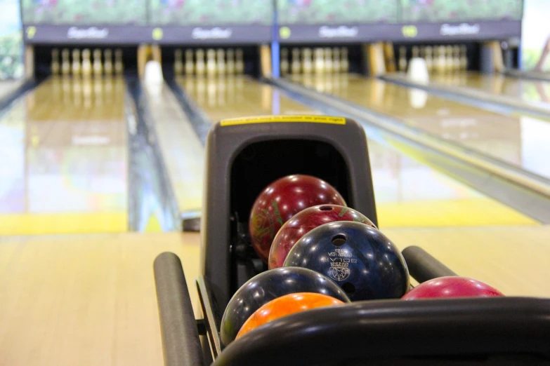 a row of bowling balls in a bowling alley, by Terese Nielsen, 7 7 7 7, from the elbow, bowl, seen from far away