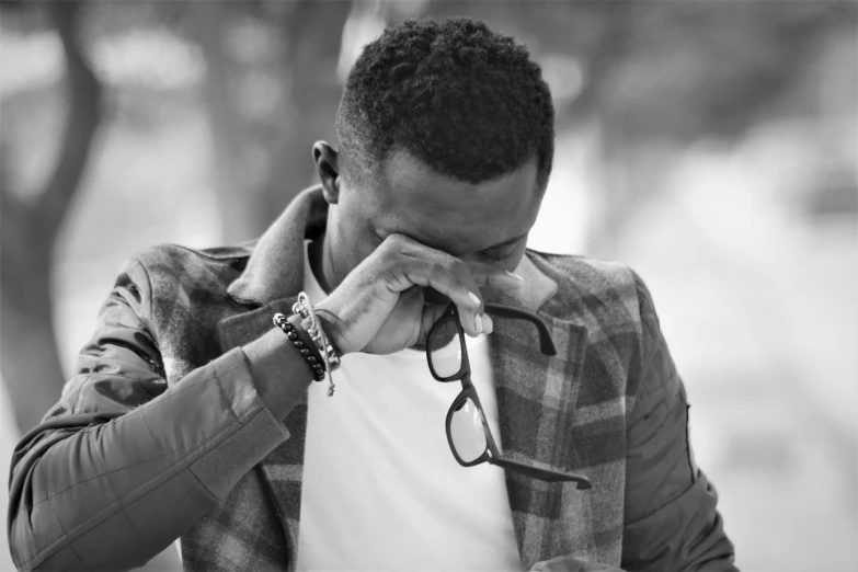 a black and white photo of a man talking on a cell phone, by Afewerk Tekle, pexels, crying fashion model, man with glasses, facepalm, comforting