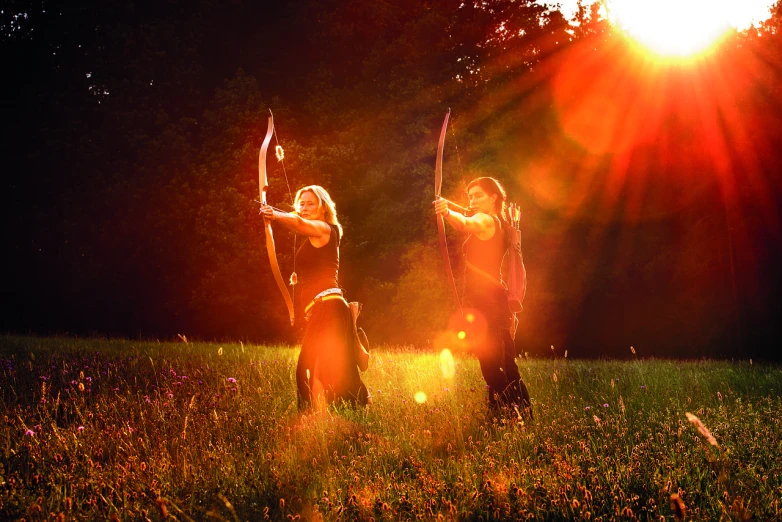 a couple of women standing on top of a lush green field, a picture, by Erwin Bowien, shutterstock, renaissance, long bow and arrows, lens flare lighting, backlight photo sample, against dark background