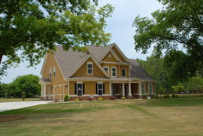 a large yellow house sitting on top of a lush green field, a picture, exterior design, exterior photo