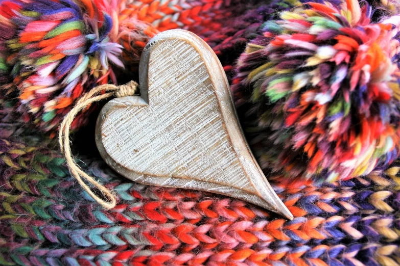a wooden heart sitting on top of a pile of yarn, a macro photograph, by Sylvia Wishart, full of colour w 1024, wintertime, cute details, beautiful look