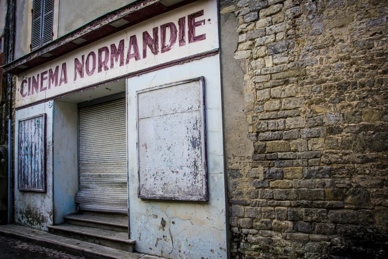 a sign that is on the side of a building, by Raymond Normand, flickr, romanesque, urbex photography, shop front, the normandy landings, a wide full shot