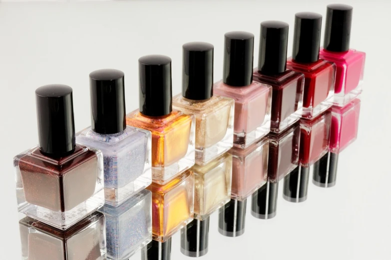 a row of nail polish bottles sitting next to each other, by Juan O'Gorman, shutterstock, yellows and reddish black, reflective gradient, wide shot photo, stock photo