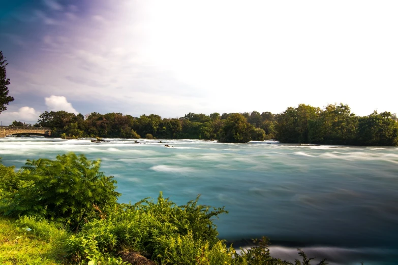 a river flowing through a lush green forest filled with trees, a tilt shift photo, niagara falls, tourist photo, long exposure photo, usa-sep 20