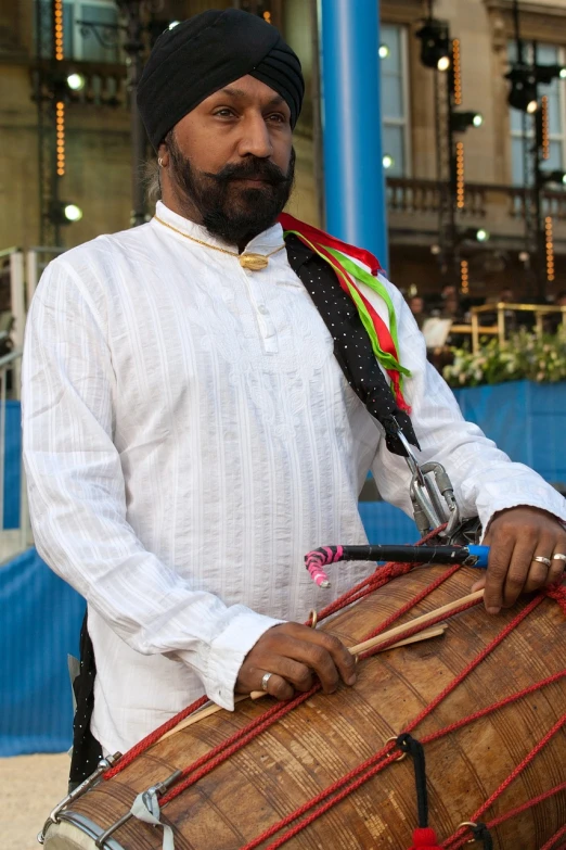a man in a turban playing a musical instrument, by David Burton-Richardson, flickr, capoeira, sheikh mohammed ruler of dubai, wearing festive clothing, black man