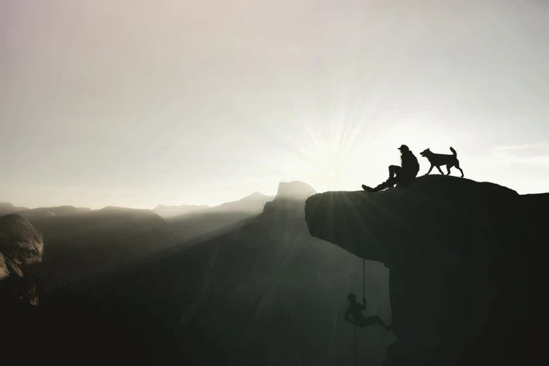 a man standing on top of a cliff next to a dog, a picture, by Kurt Roesch, silhouette, belaying, humans exploring, sitting cutely on a mountain