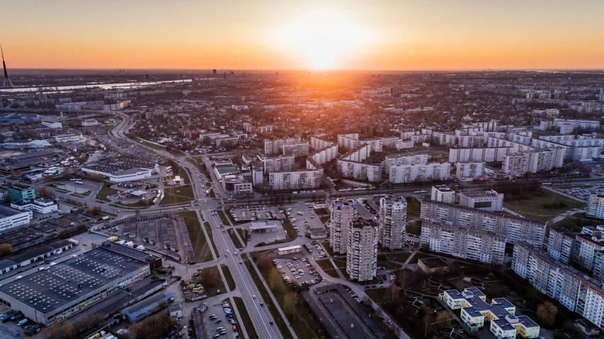 an aerial view of a city at sunset, a picture, by Adam Marczyński, shutterstock, espoo, warsaw, surrounding cinematic light, high detailed photo