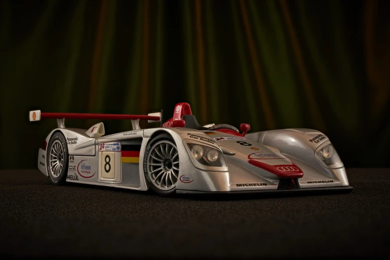 a silver and red race car on a black surface, a 3D render, polycount contest winner, photorealism, tilt - shift photography, sports car in the room, paul barson, polaroid octane render