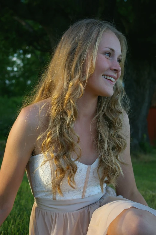 a beautiful young woman sitting on top of a lush green field, by Christen Købke, flickr, long blond drill curls, grinning lasciviously, early evening, wearing a white sundress