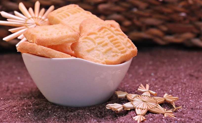 a bowl filled with crackers sitting on top of a table, by Sylvia Wishart, pexels, folk art, embossed, cross, vanilla, starburst