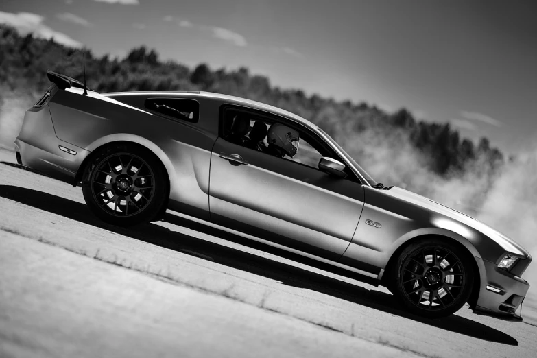 a black and white photo of a mustang, by Andrew Domachowski, unsplash, on a racetrack, shiny silver, 2012, high render