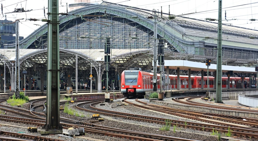 a red train traveling past a train station, a picture, by Karl Völker, pixabay, happening, red trusses, img _ 9 7 5. raw, berlin, terminals