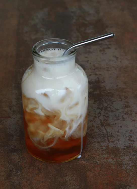 a close up of a drink in a jar on a table, inspired by Tan Ting-pho, stainless steal, cloud, long arm, caramel