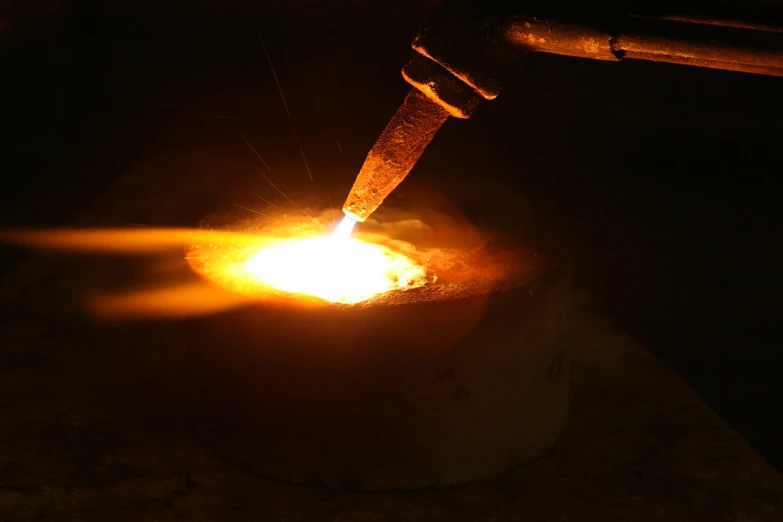 a person cutting a piece of metal with a knife, an engraving, by Aleksander Gierymski, flickr, gas lighting, molten plastic, round form, golden glow