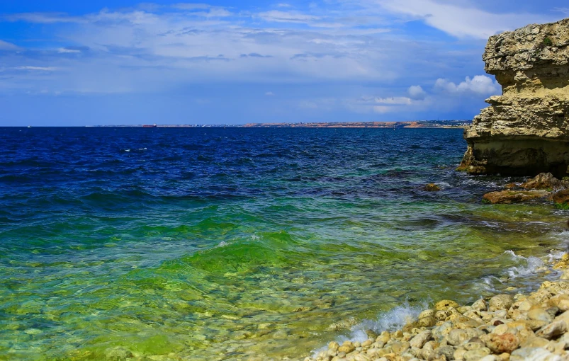 a large body of water next to a rocky shore, a picture, by Alexander Fedosav, shutterstock, romanticism, green and blue colors, vacation photo, very beautiful photo, bright vivid colors