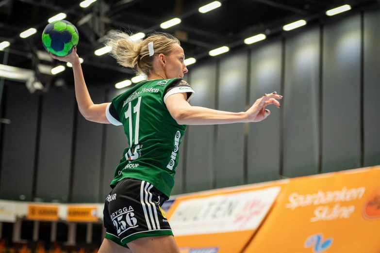 a woman in a green shirt and black shorts playing a game of volleyball, a picture, by Oskar Lüthy, happening, novi stars, halfing, indoor shot, lynn skordal