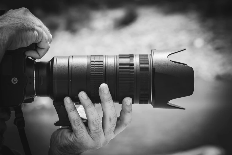 a close up of a person holding a camera, a black and white photo, by Mirko Rački, pixabay, canon- 70-200mm lens, stacked image, telephoto zoom, commercial product photography