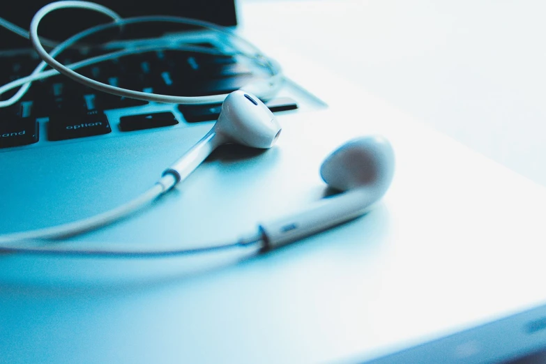 a pair of ear buds sitting on top of a laptop, pexels, screengrab, white and pale blue toned, shot on iphone 6, mythological