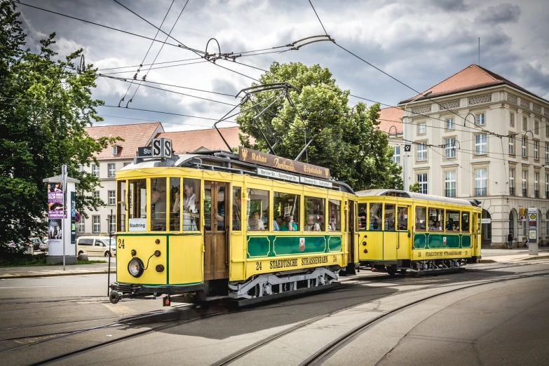 a yellow and green trolley traveling down a street, by Sigmund Freudenberger, shutterstock, hannover, twins, fair, preserved historical