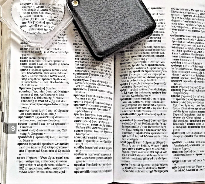 a cell phone sitting on top of an open book, a stipple, photorealism, magnifying glass, random english words, close-up 35mm macro shot, bible