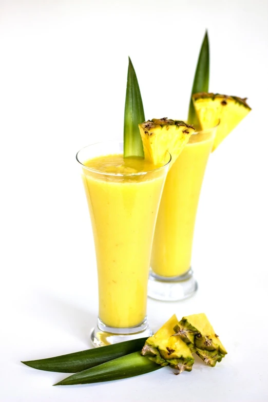 two glasses of smoothie with pineapple garnish, by Juan O'Gorman, on a white background, istockphoto, islamic, tall shot